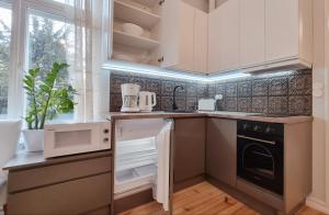 a kitchen with white cabinets and a stove top oven at Aia Center Apartment with sauna in Pärnu