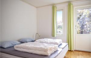 a bedroom with a bed with white sheets and a window at 3 Bedroom Cozy Home In Forsand in Jørpeland