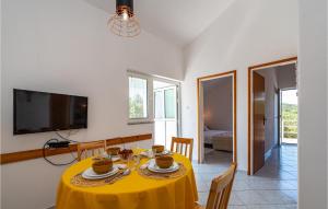 ein Esszimmer mit einem gelben Tisch mit Stühlen und einem TV in der Unterkunft 2 Bedroom Nice Home In Molat in Molat