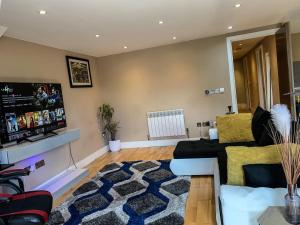 a living room with a couch and a flat screen tv at Entire 2 bedroom Apartment in Kingston upon Thames