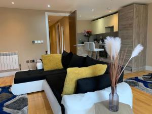 a living room with a black couch and yellow pillows at Entire 2 bedroom Apartment in Kingston upon Thames