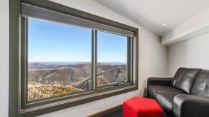 a living room with a couch and a large window at Alpine Heights 27 in Mount Hotham