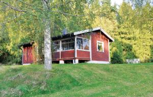 een rood huis in een veld met een boom bij 2 Bedroom Lovely Home In ml in Ånimskog