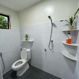 La salle de bains blanche est pourvue d'une douche et de toilettes. dans l'établissement Cabin in the Woods by Abris, à Bukit Gambir