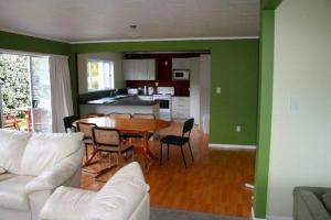 a living room with a table and chairs and a kitchen at Matapouri Cottage - Matapouri Holiday Home in Matapouri