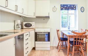 uma cozinha com armários brancos e uma mesa e cadeiras em Awesome Home In Holmefjord With House Sea View em Holmefjord