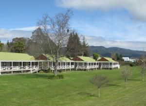 a white building with a green roof in a field at Turangi Bridge Motel in Turangi