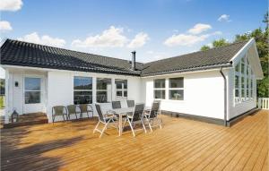 a white house with a deck with chairs and a table at 4 Bedroom Cozy Home In Auklandshamn in Vestvik +7 photos