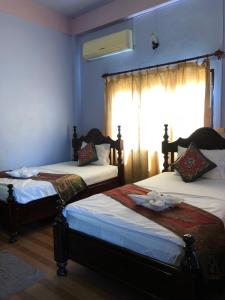 two beds in a room with a window at Soutjai Guesthouse & Restaurant in Vang Vieng