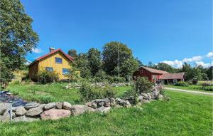 a yellow house with a stone wall in a yard at Nice Apartment In Svanesund With House Sea View in Svanesund