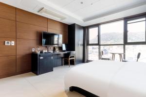 een slaapkamer met een bed, een bureau en een televisie bij Browndot Hotel Incheon Songdo in Incheon