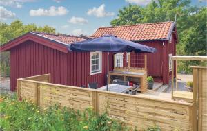 een rode schuur met een paraplu op een houten terras bij Gorgeous Home In Tystberga With Kitchen in Tystberga