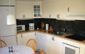 cocina con armarios blancos, fregadero y mesa en 2 Bedroom Gorgeous Home In Bodafors, en Bodafors