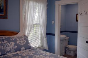 a bedroom with a bed and a window with a toilet at Strathaird Bed and Breakfast in Niagara Falls