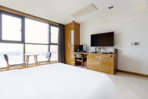 a hotel room with a bed and a desk with a television at Browndot Hotel Incheon Songdo in Incheon