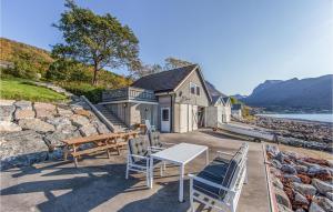 a patio with a table and chairs and a house at Nice Home In Hundeidvik With Ethernet Internet in Hundeidvik