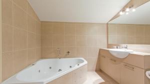 a bathroom with a bath tub and a sink at Chalet Hotham 20 in Mount Hotham
