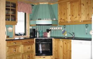 a kitchen with wooden cabinets and a black stove top oven at 5 Bedroom Amazing Home In Kvinlog in Stakkeland