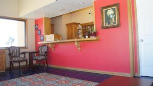 Habitación con pared roja, mesa y sillas. en Holiday Lodge & Suites, en McAlester
