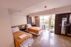 a hotel room with two beds and a balcony at 5880 Enriquez Residences in Manila