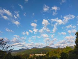 un cielo azul con nubes y montañas en el fondo en Pension Izukogen, en Ito