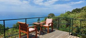 twee stoelen en een tafel op een terras met uitzicht op de oceaan bij BOHALI'S HOUSE in Sinarádes