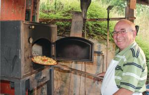 a man is taking a pizza out of an oven at Cozy Apartment In Grfendorf With House A Panoramic View in Gräfendorf