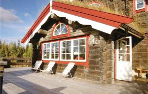 a cabin with white chairs on a wooden deck at Cozy Home In Sälen With Sauna in Stöten