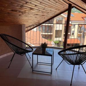 Duas cadeiras e uma mesa numa varanda com vista em Deluxe Central Rooms em Karlovo