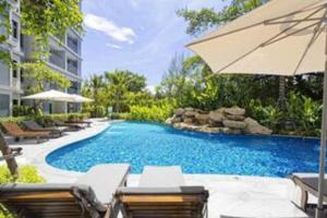 a swimming pool with chairs and an umbrella at Nayang Beach Brand New Executive Luxury Condo in Nai Yang Beach