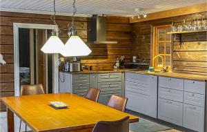Cozy Home In Vemdalen With Sauna في فيمدالين: مطبخ بجدران خشبية وطاولة مع كراسي