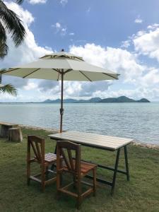 een tafel en stoelen onder een paraplu naast het water bij Koh Yao Yai Sea Breeze House เกาะยาวใหญ่ซีบรีซเฮ้าส์ in Ko Yao Yai