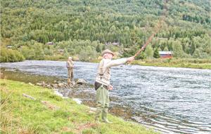 two people standing on the bank of a river fishing at Beautiful Home In Sogndal With House Sea View in Svidalen