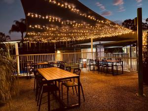a patio with tables and chairs with lights on it at John Hunter Motel Muswellbrook in Muswellbrook