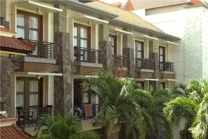 a building with palm trees in front of it at La Walon Hotel in Kuta