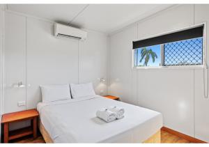 a white bedroom with a bed with two towels on it at Discovery Parks - Mackay in Mackay