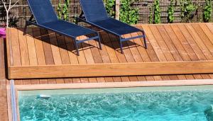 two chairs sitting on a deck next to a swimming pool at La Maison Bastide in Bordeaux