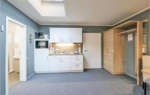cocina con armarios blancos y nevera en Cozy Apartment In Dagebll With Wifi, en Dagebüll
