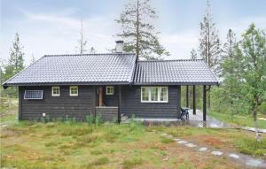 a small black house in the middle of a field at Cozy Home In Rendalen With Sauna in Akrestrommen