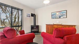 a living room with two red chairs and a fireplace at Karoondah 10 in Mount Hotham