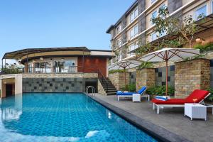 a swimming pool with two lounge chairs and a building at Azana Boutique Hotel Denpasar in Denpasar