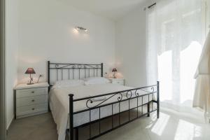 a white bedroom with a bed and a window at Gurosai in Dorgali