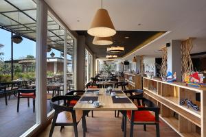a restaurant with wooden tables and chairs and windows at Azana Boutique Hotel Denpasar in Denpasar