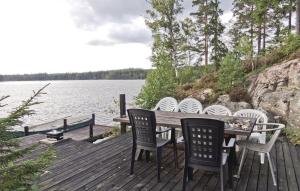 a wooden deck with a table and chairs next to a lake at Gorgeous Home In Lammhult With House Sea View in Asaryd