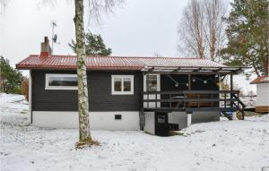 ein Haus mit einer Terrasse im Schnee in der Unterkunft Stunning Home In Hjlteby With Kitchen in Hjälteby