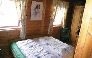 a bedroom with a bed in a wooden room with two windows at Cozy Home In Lyngdal With Kitchen in Osestad