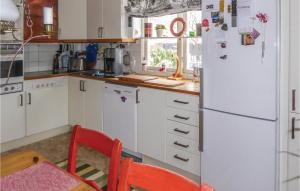 Lovely Home In Spnga With Kitchen في ستوكهولم: مطبخ فيه دواليب بيضاء وثلاجة بيضاء