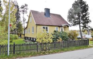 a yellow house with a fence in front of it at Lovely Home In Spnga With Kitchen in Stockholm