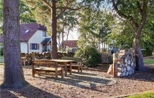 a picnic table and benches in a park with trees at 1 Bedroom Gorgeous Home In Fuhlendorf in Fuhlendorf