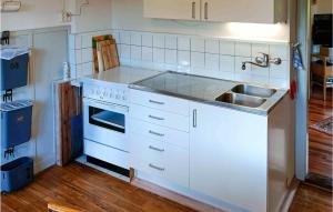 a white kitchen with a sink and a stove at Holiday Home Sandsjöfors 47 in Holsteryd